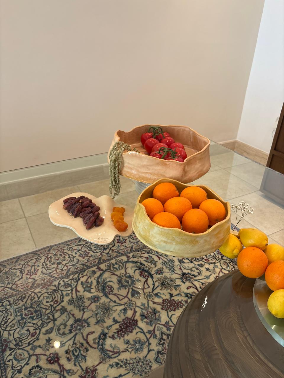 Tomato, orange, and dates bowls styled on rug